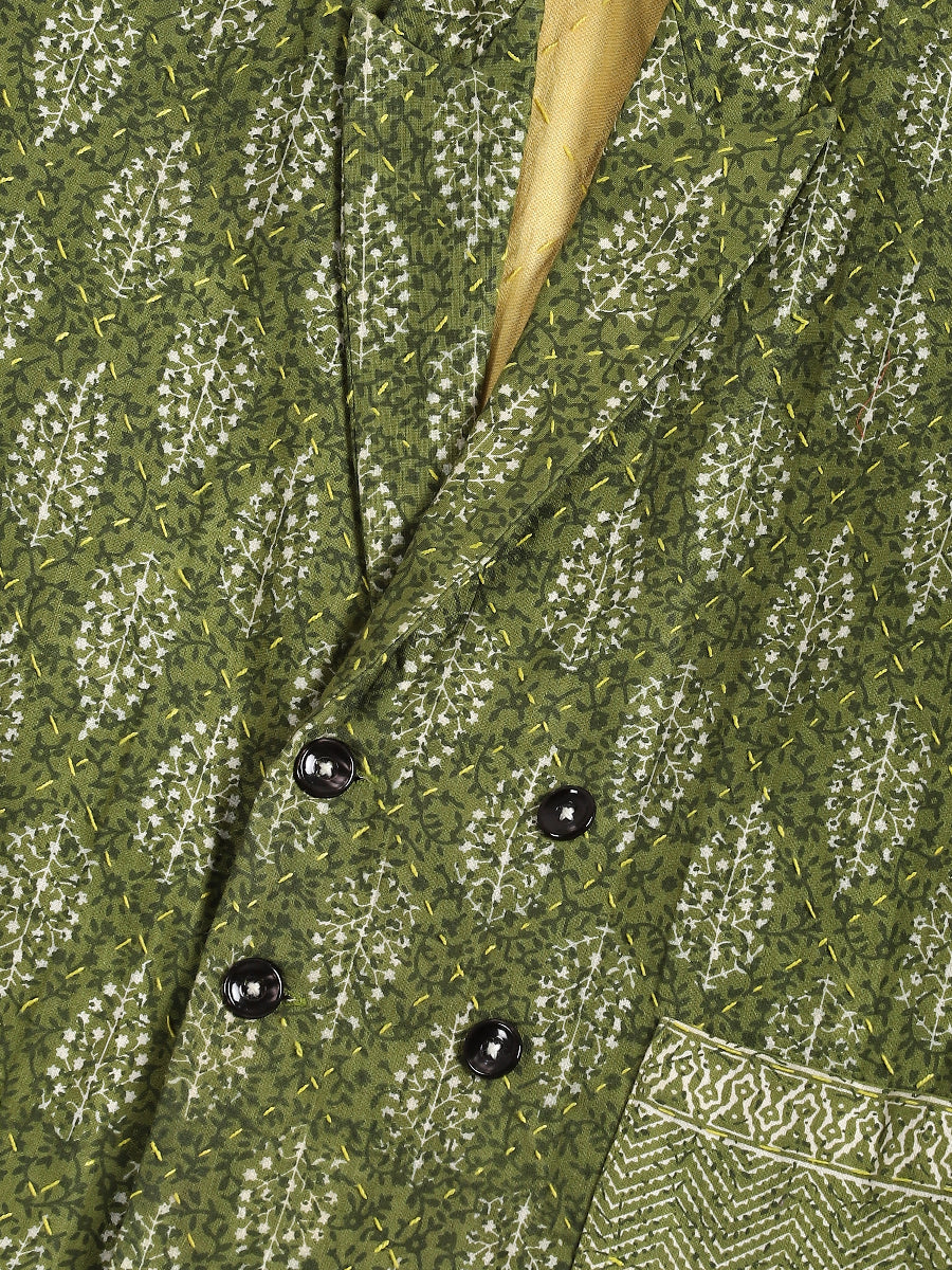 Close-up of a textured green fabric with black beads and a wooden stick.