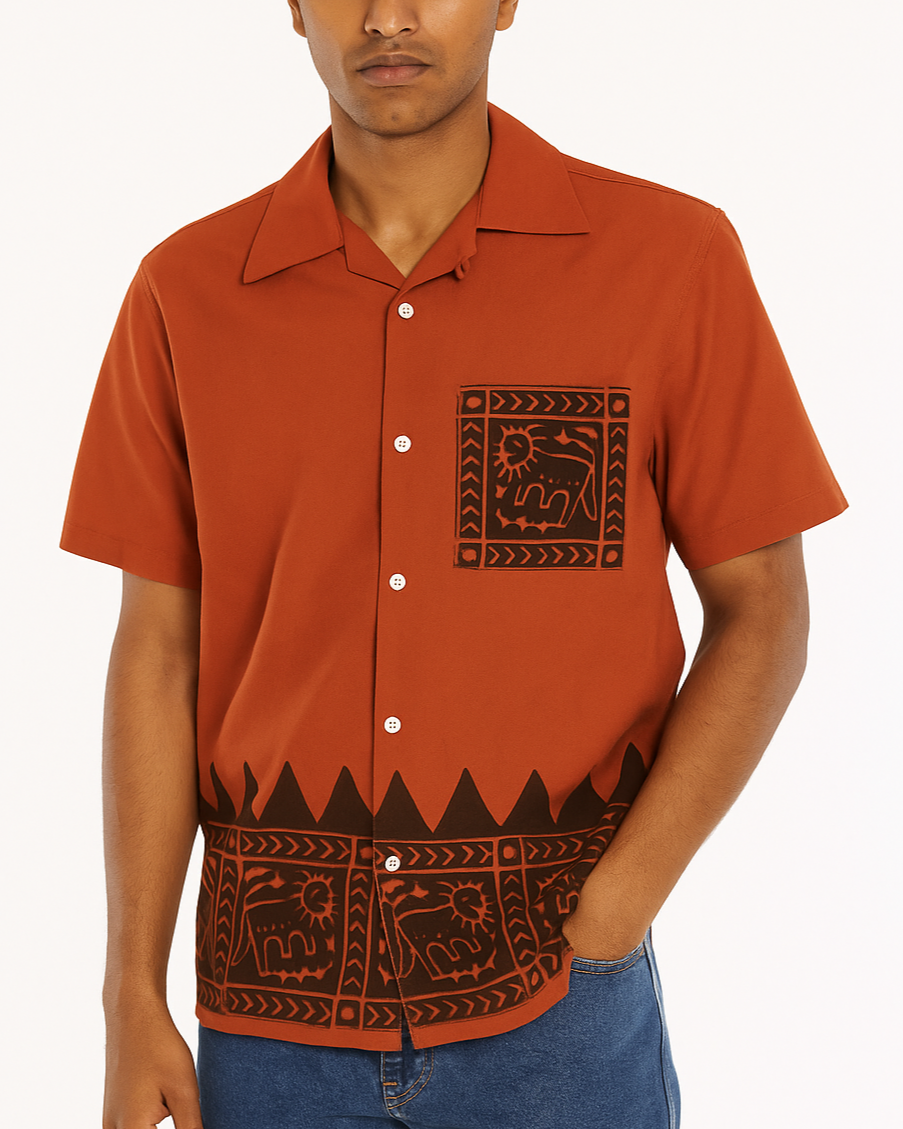 Man wearing a brown button-up shirt with a pattern, standing against a white background