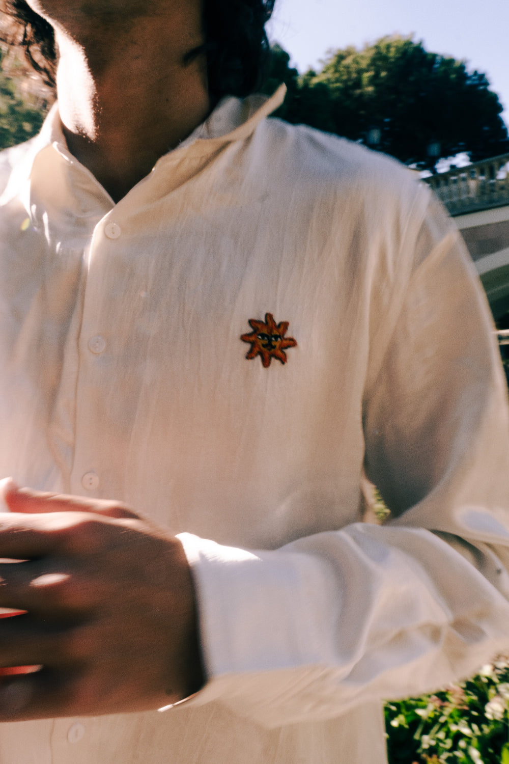 Person wearing a white shirt with a decorative brooch outdoors