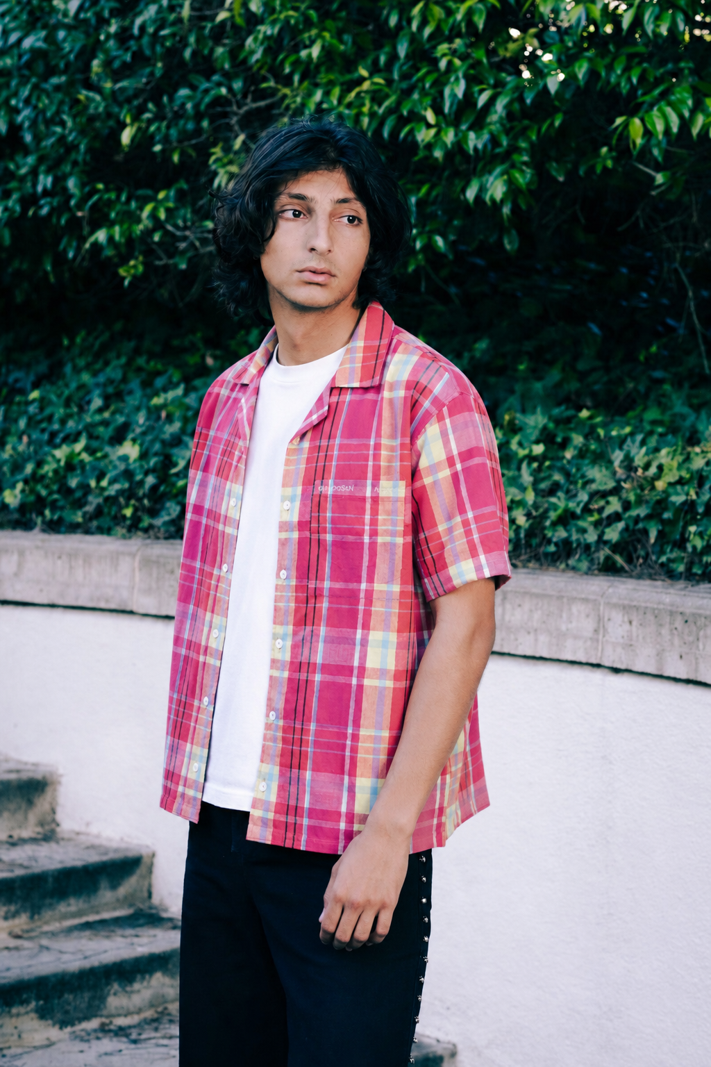 Man wearing a red plaid short-sleeve shirt over a white t-shirt outdoors – Hindostan Archive