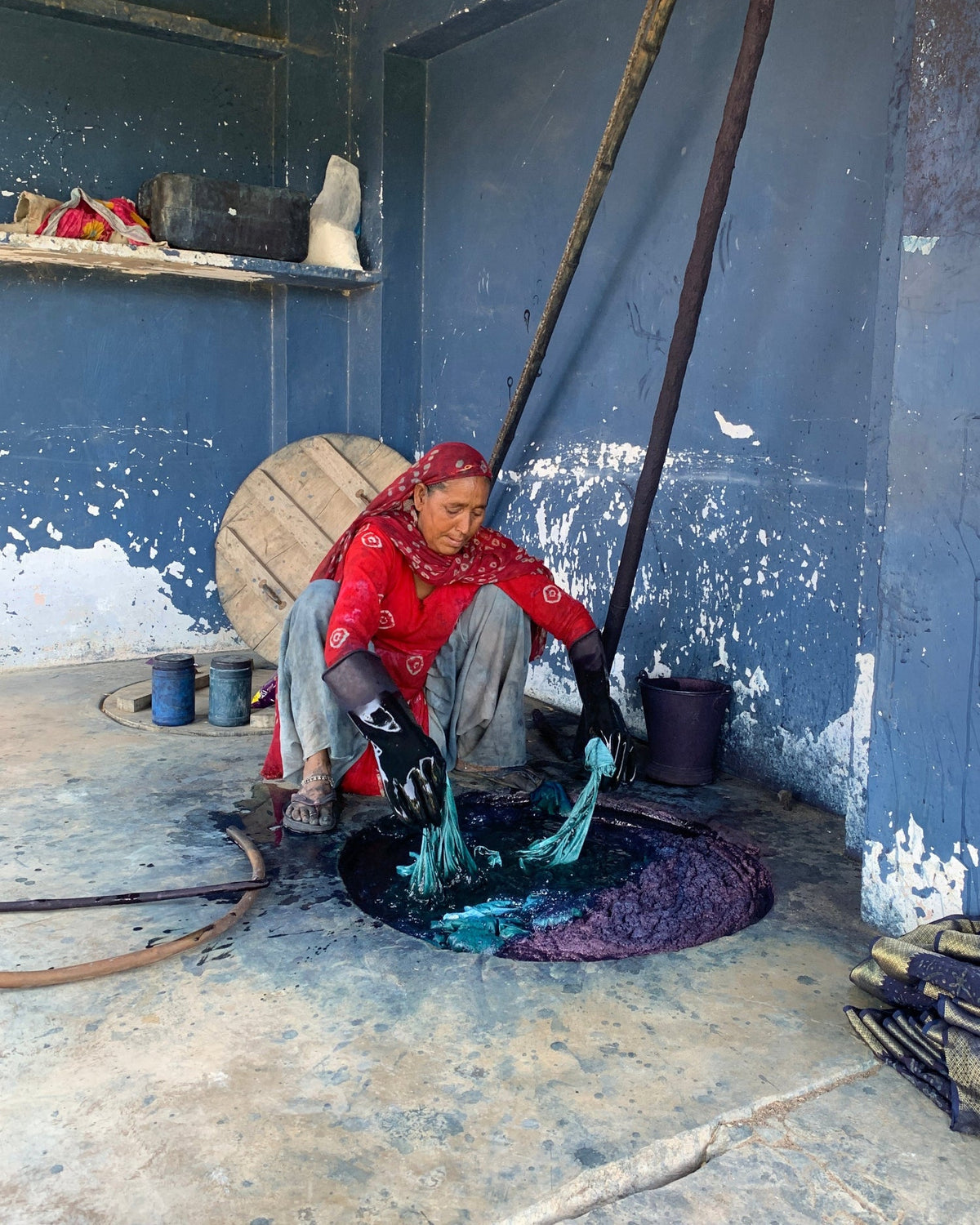 Person sitting on a step with a blue wall and concrete floor in the background