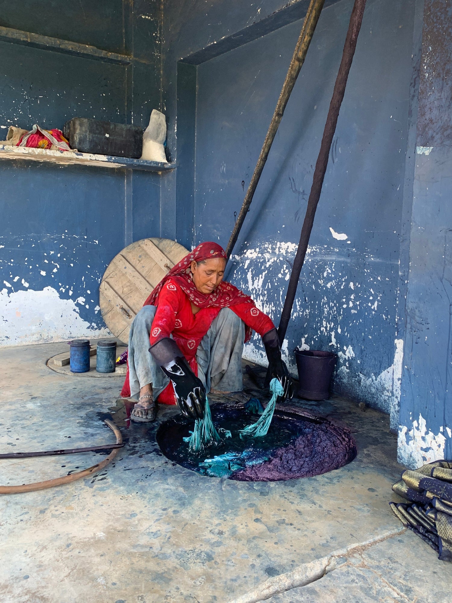 Person sitting on a step with a blue wall and concrete floor in the background